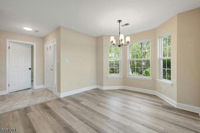 unfurnished room with visible vents, baseboards, a chandelier, and light wood finished floors