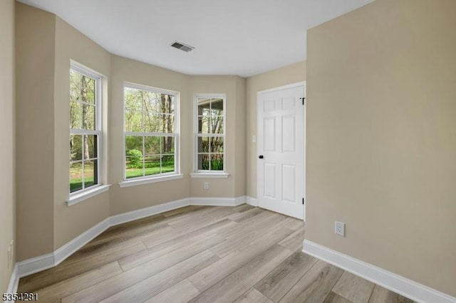 spare room featuring visible vents, baseboards, and wood finished floors