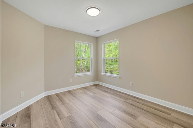 spare room with baseboards and light wood-style floors