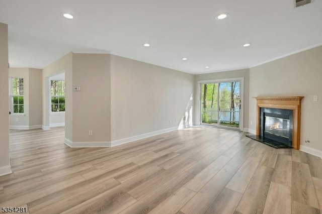 unfurnished living room with a glass covered fireplace, light wood-style flooring, recessed lighting, baseboards, and visible vents