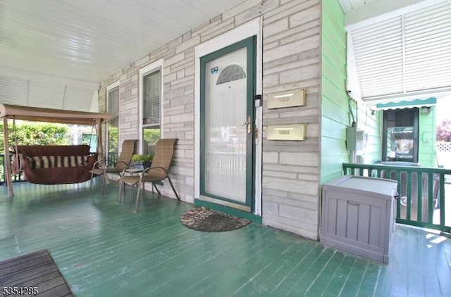 entrance to property with covered porch and stone siding
