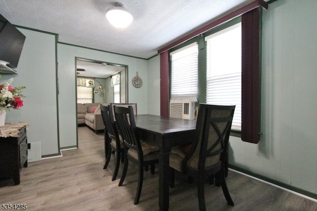 dining space featuring light wood-style flooring and a decorative wall