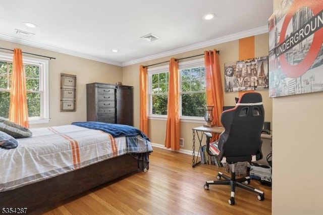 bedroom featuring baseboards, visible vents, multiple windows, and wood finished floors