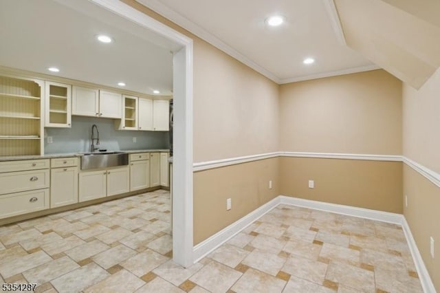 kitchen featuring glass insert cabinets, recessed lighting, light countertops, cream cabinetry, and a sink