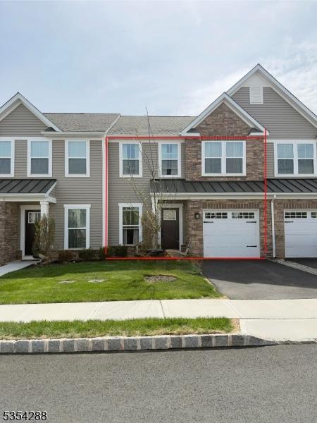 townhome / multi-family property featuring a standing seam roof, driveway, metal roof, a front yard, and a garage
