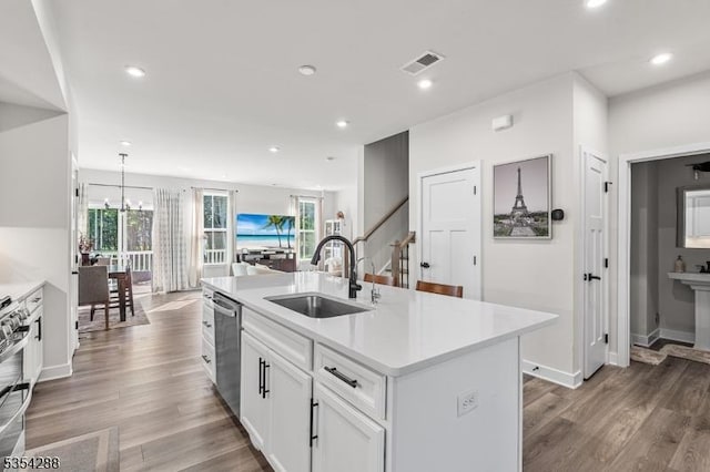 kitchen with a center island with sink, dishwasher, a sink, light countertops, and white cabinetry