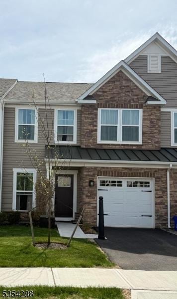 townhome / multi-family property featuring a garage, a front yard, a standing seam roof, metal roof, and driveway