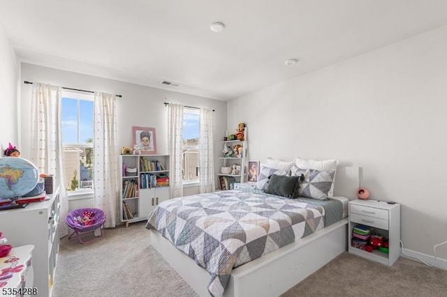 carpeted bedroom with visible vents and multiple windows