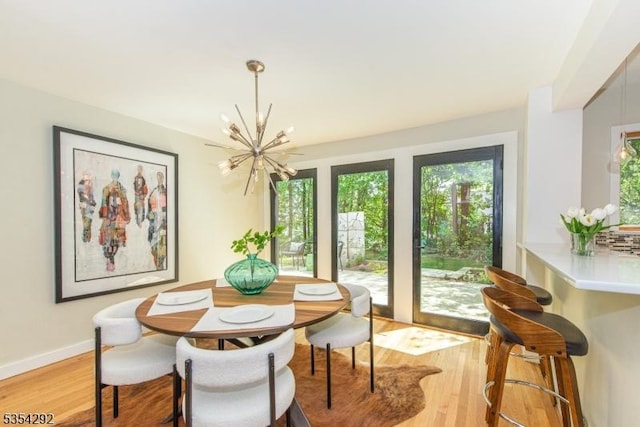 dining room with light wood-style floors, a notable chandelier, and a healthy amount of sunlight