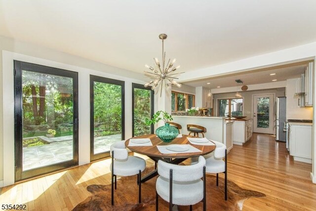 dining space featuring a chandelier, plenty of natural light, and light wood-style flooring