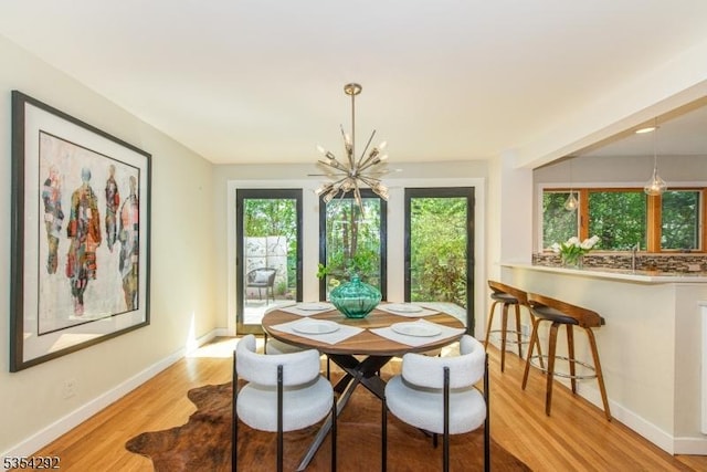 dining room with baseboards, a chandelier, a healthy amount of sunlight, and light wood finished floors
