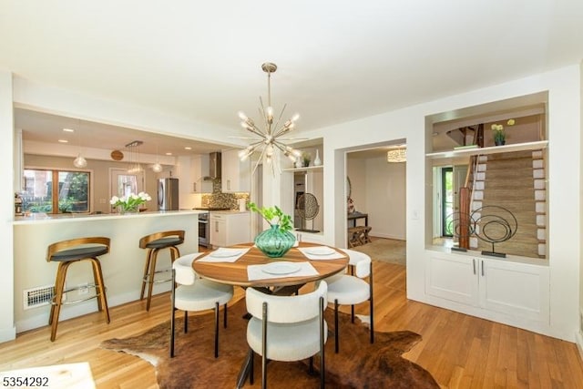 dining room featuring plenty of natural light, light wood-style flooring, and a chandelier