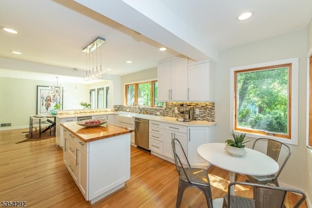 kitchen with stainless steel dishwasher, white cabinetry, butcher block counters, and tasteful backsplash