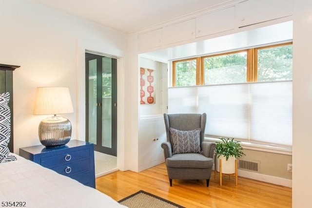 bedroom with visible vents, ornamental molding, and light wood-type flooring