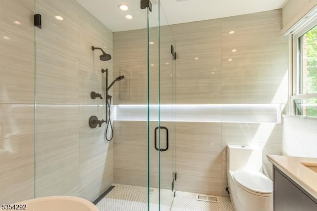full bathroom featuring vanity, toilet, tile walls, tile patterned floors, and a stall shower