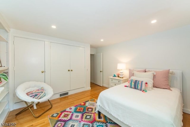 bedroom with a closet, recessed lighting, light wood-style flooring, and visible vents