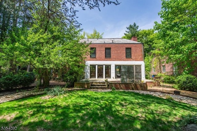 back of property featuring a lawn, a chimney, and a sunroom