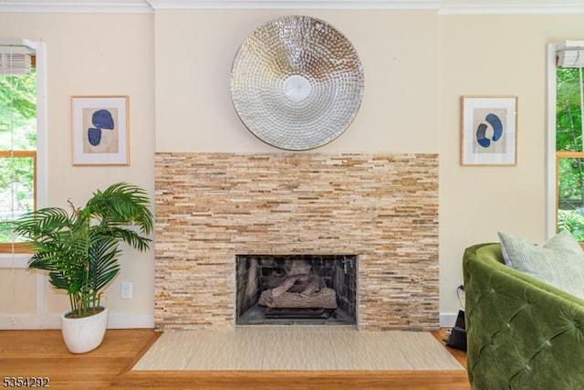 living area with crown molding, baseboards, a fireplace with flush hearth, and wood finished floors