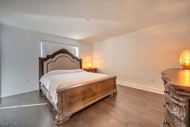 bedroom with baseboards and dark wood-type flooring