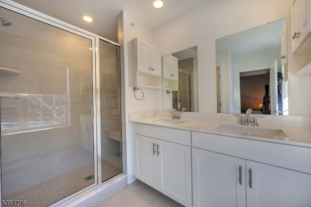 bathroom featuring a sink, a stall shower, and double vanity