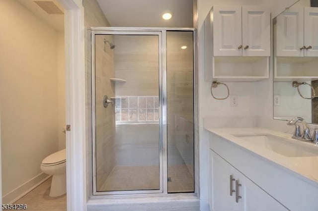 bathroom with vanity, toilet, visible vents, and a stall shower