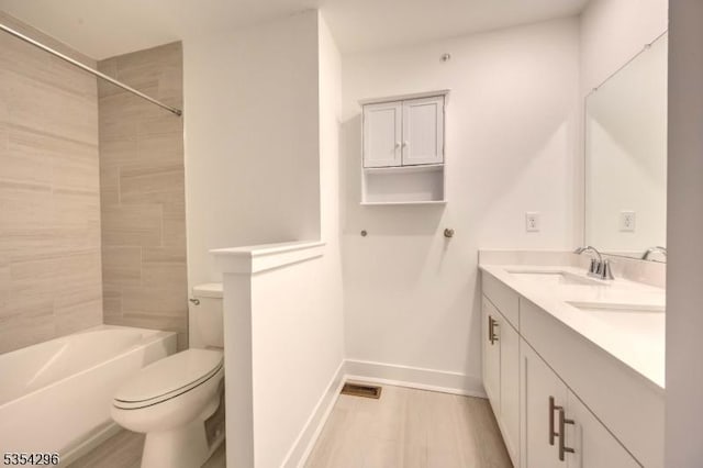 full bath featuring double vanity, wood finished floors, a sink, baseboards, and toilet