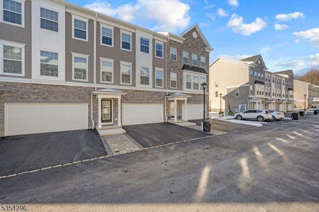 view of building exterior with a residential view, an attached garage, and aphalt driveway