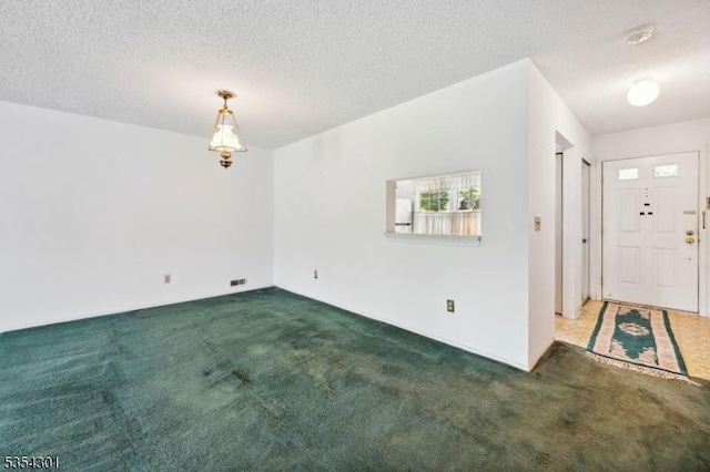 foyer entrance featuring carpet flooring and a textured ceiling