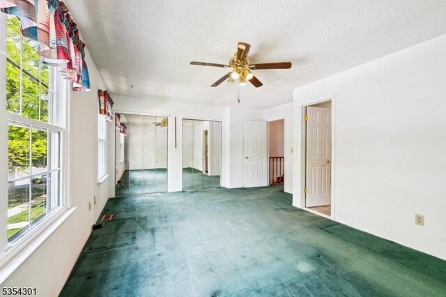 unfurnished bedroom with carpet floors, multiple closets, and a ceiling fan