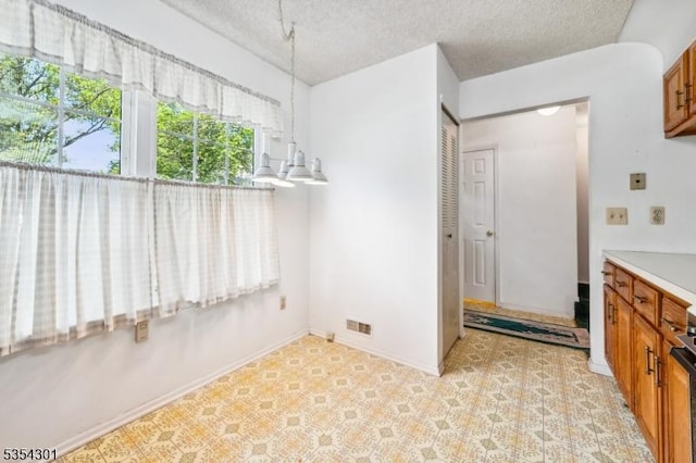 unfurnished dining area featuring a textured ceiling and baseboards