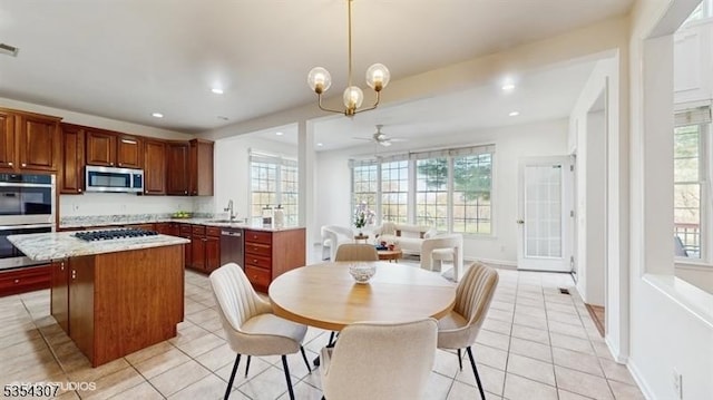 kitchen featuring light tile patterned floors, light countertops, stainless steel appliances, and ceiling fan with notable chandelier