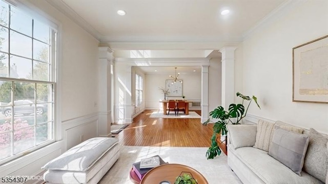 living room with ornate columns, ornamental molding, plenty of natural light, and wood finished floors