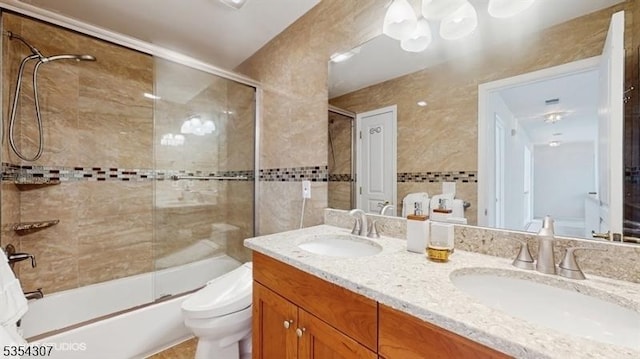 bathroom with double vanity, toilet, enclosed tub / shower combo, and a sink