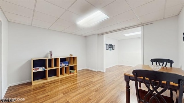 dining room featuring light wood-type flooring, baseboards, and a drop ceiling