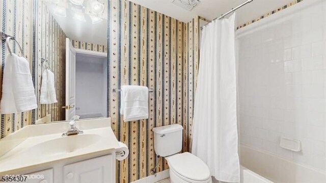 bathroom featuring toilet, wallpapered walls, shower / bath combo, and vanity