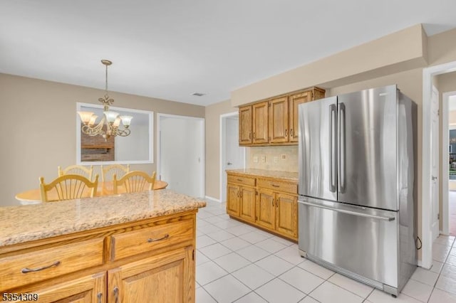 kitchen with freestanding refrigerator, light tile patterned flooring, a chandelier, backsplash, and decorative light fixtures