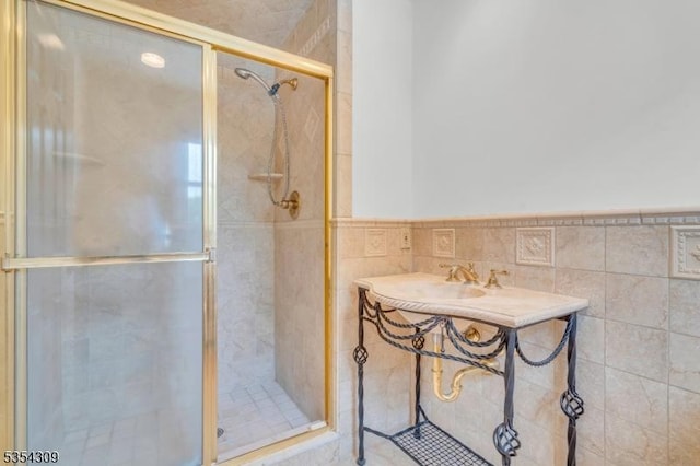 bathroom with a shower stall, wainscoting, and tile walls