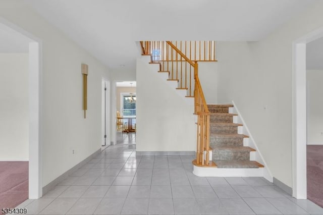 stairs with tile patterned floors, baseboards, and a chandelier