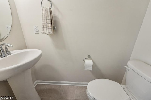 bathroom featuring toilet, baseboards, and a sink
