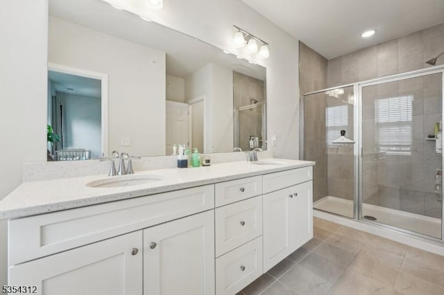 bathroom featuring a sink, tile patterned flooring, a shower stall, and double vanity