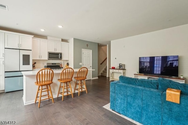 living area with visible vents, stairs, baseboards, dark wood-style floors, and recessed lighting