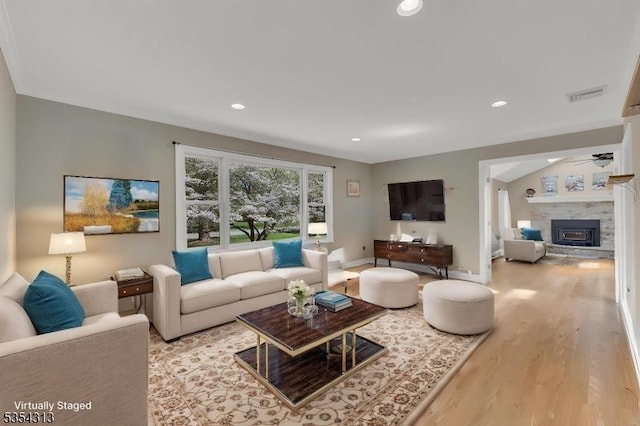 living area with visible vents, wood finished floors, a fireplace, baseboards, and ceiling fan