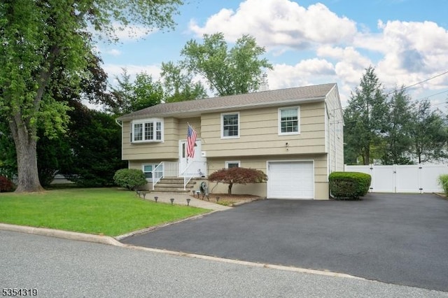 split foyer home with fence, a garage, a front yard, a gate, and driveway