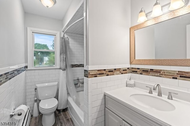 bathroom featuring baseboard heating, vanity, toilet, a wainscoted wall, and tile walls