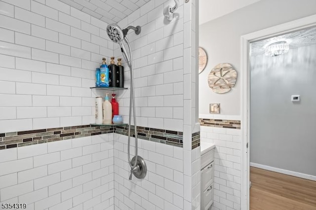 full bath featuring tile walls, a tile shower, and wood finished floors