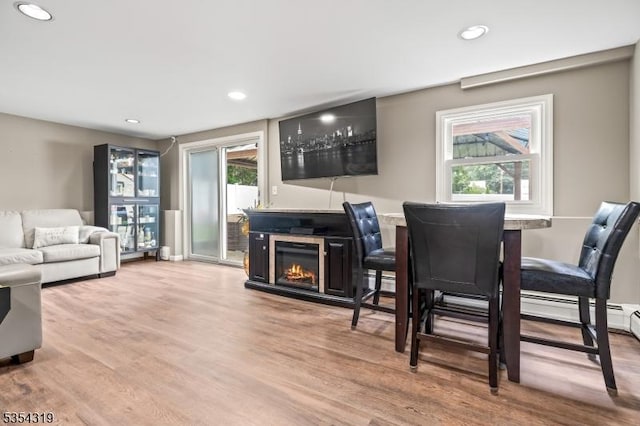 bar with baseboard heating, recessed lighting, a glass covered fireplace, and wood finished floors