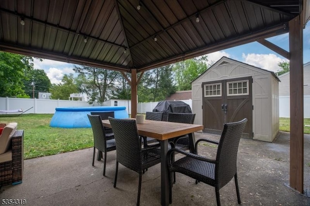 view of patio with outdoor dining area, an outbuilding, a fenced backyard, and a storage shed