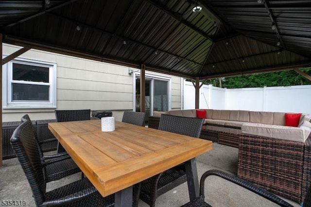 view of patio / terrace featuring an outdoor living space, outdoor dining space, fence, and a gazebo