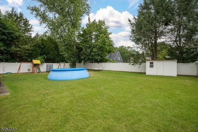 view of yard with a fenced backyard, an outdoor structure, a playground, and a storage shed