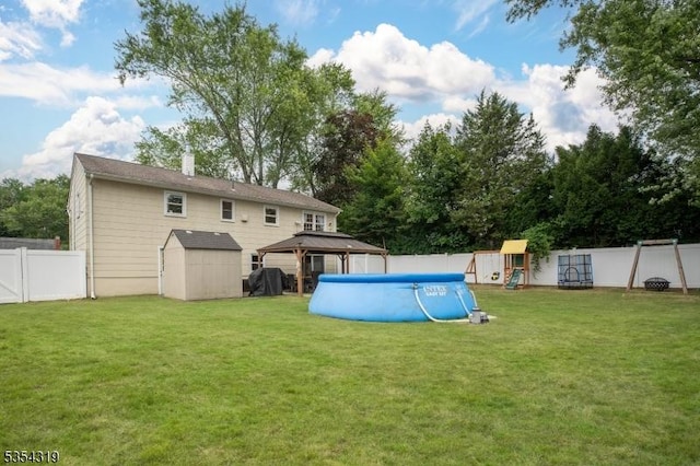 back of property with a lawn, a fenced backyard, a playground, and a storage shed